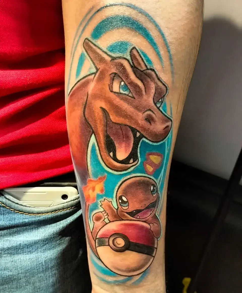 Tatuaje a todo color de Charizard y Charmander con una pokebola, en el brazo, por Jenn Tatts
