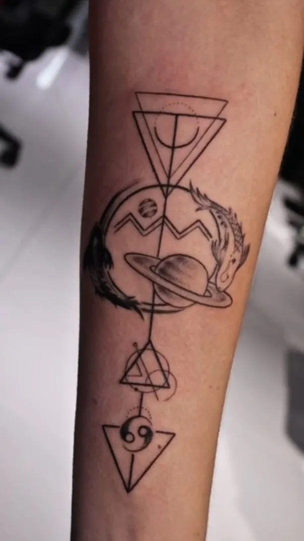 Tatuaje geométrico en línea con un planeta, triángulos y símbolos, en el antebrazo, por Jenn Tatts
