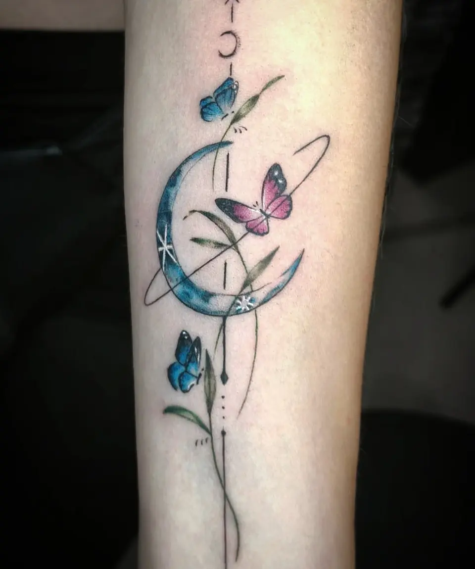 Tatuaje fine line a color de una luna con mariposas en el antebrazo, por Jenn Tatts
