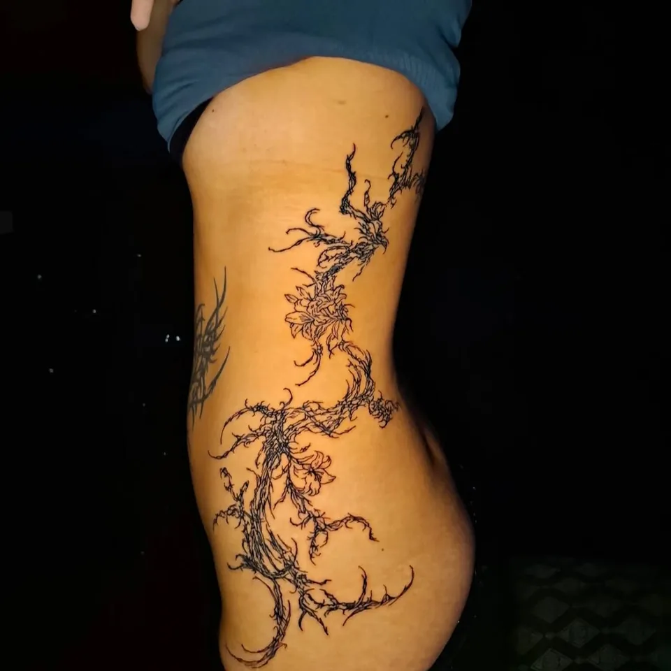 Tatuaje de ramas y raíces finas que recorren el costado, por Kewyn Romero