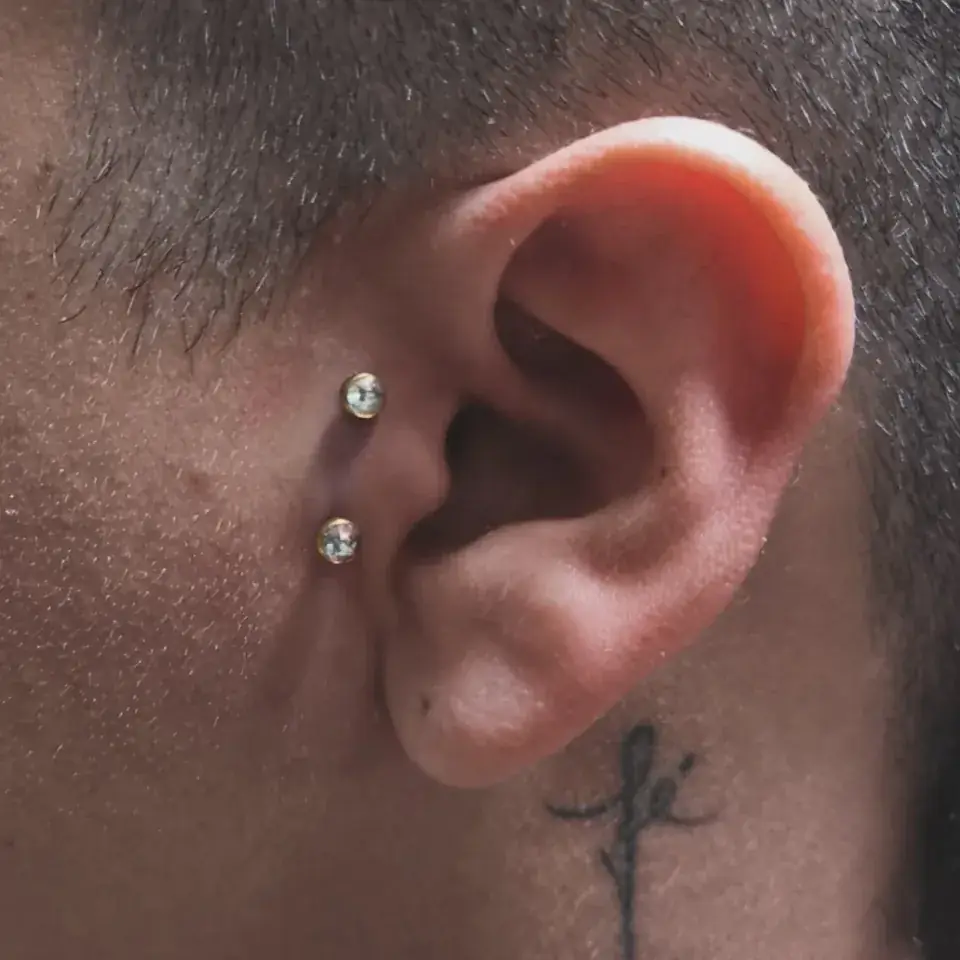 Dos perforaciones con joya de brillante en el cartílago de una oreja