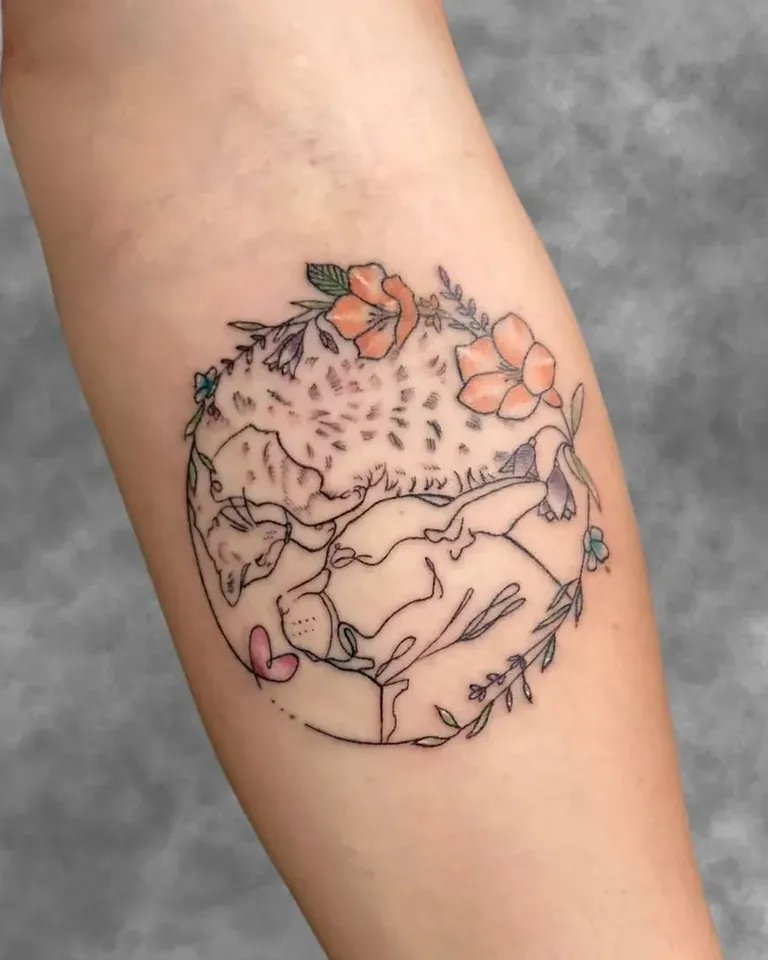 Tatuaje en línea fina de un animal dormido rodeado de flores dentro de un círculo, en el antebrazo