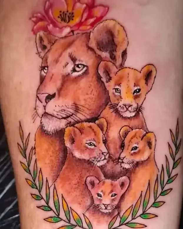 Tatuaje a color de una leona con sus cachorros dentro de una corona de laurel, en el antebrazo