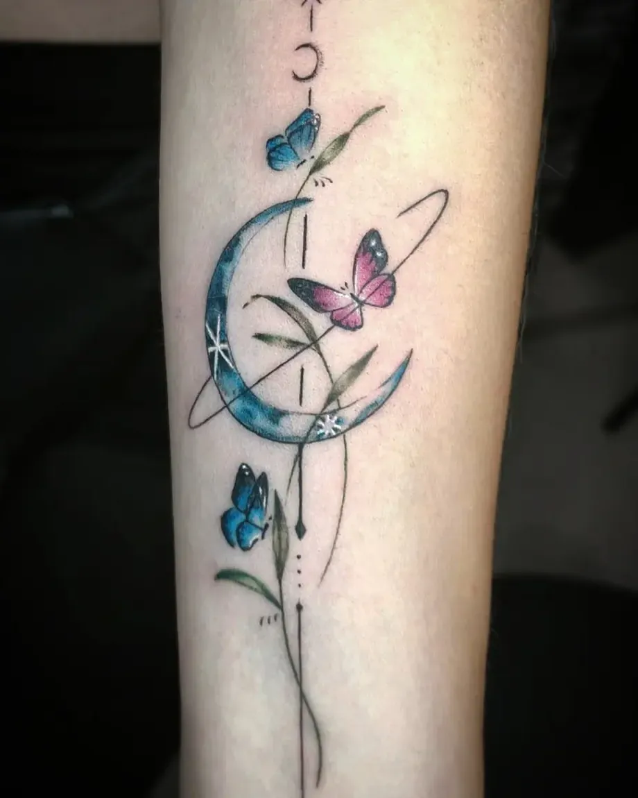 Tatuaje fine line a color de una luna con mariposas en el antebrazo