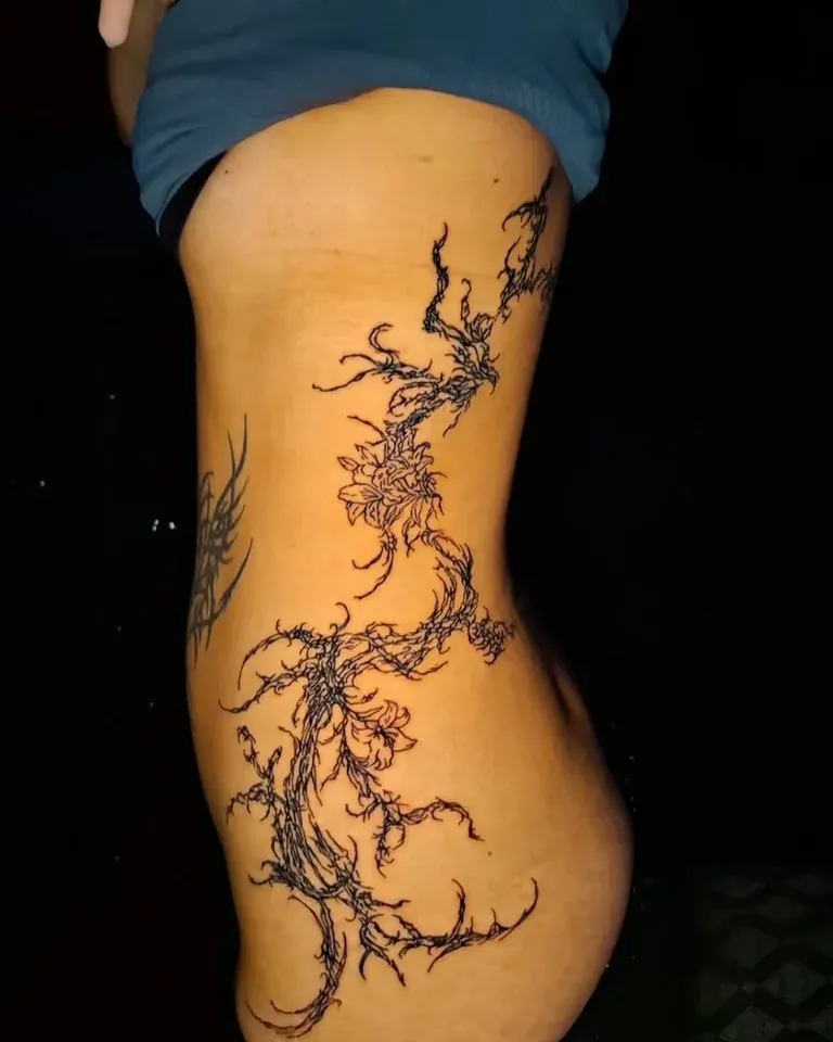 Tatuaje de ramas y raíces finas que recorren el costado
