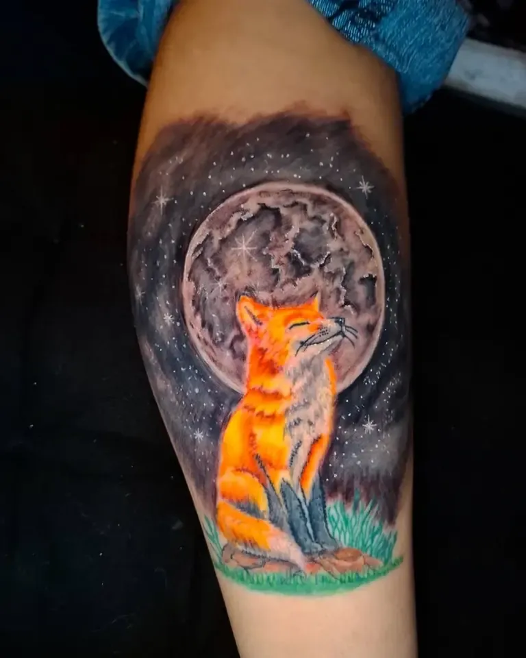 Tatuaje a todo color de un zorro frente a la luna llena en el brazo
